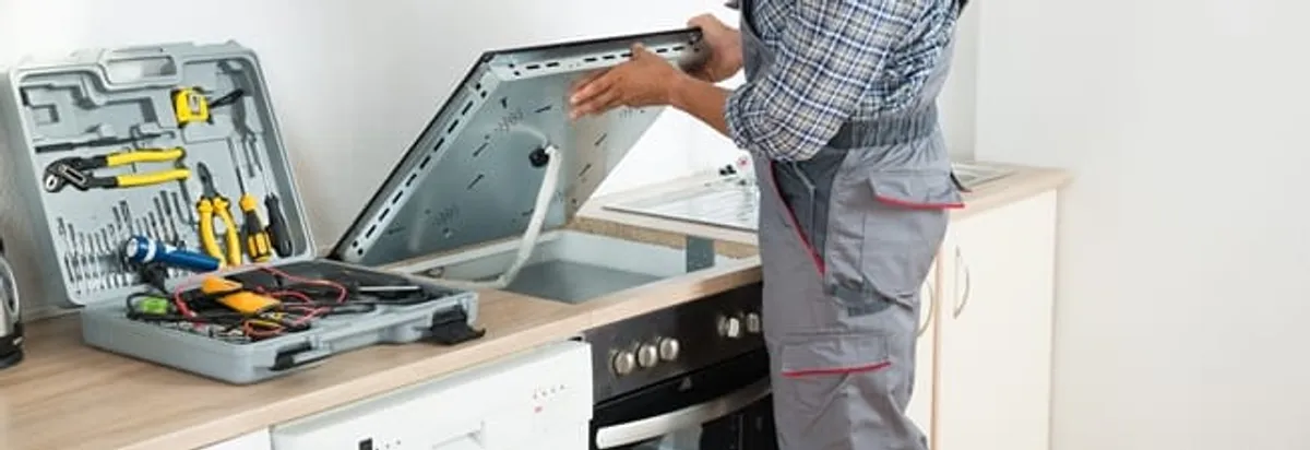 Cooktop repair technician lifting a built-in stovetop for service in Orlando, FL