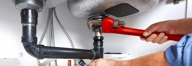 Garbage disposal repair technician tightening the sink drain and disposal connection in Orlando, FL