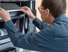 Appliance repair technician replacing a microwave vent filter in Orlando, FL