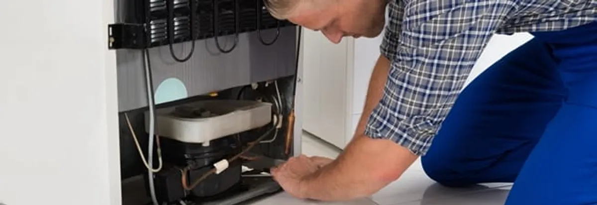 Refrigerator repair technician servicing the compressor and condenser area in Orlando, FL