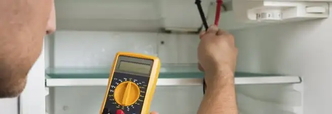 Refrigerator repair technician testing electrical components with a multimeter in Orlando, FL