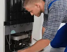 Refrigerator repair technician servicing the compressor and condenser area in Orlando, FL