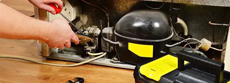 Refrigerator repair technician fixing the compressor and wiring in Orlando, FL
